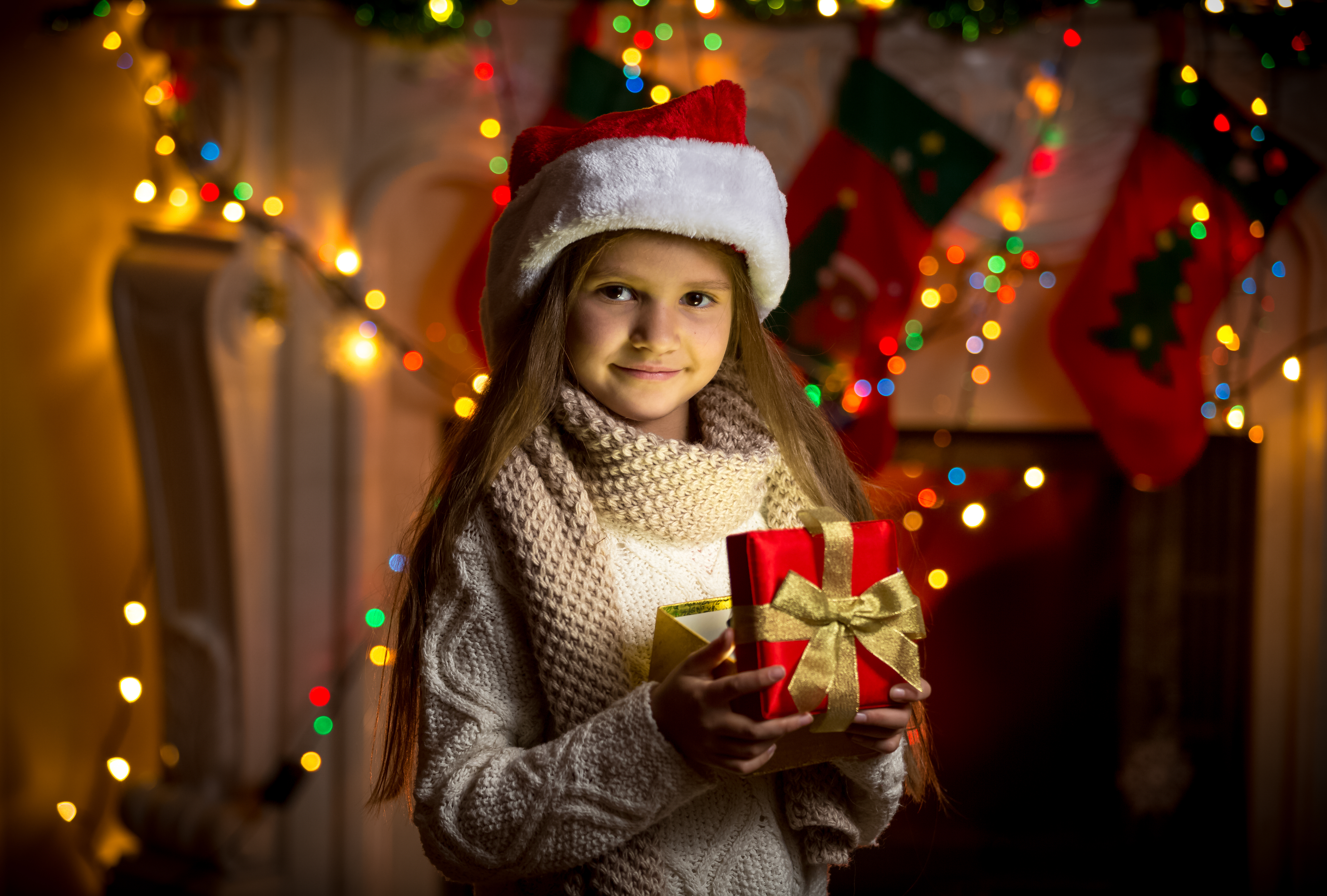 A child smiling while opening a Christmas gift